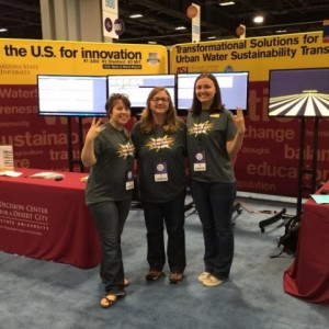 DCDC staff stand in front of booth, smiling and flashing ASU pitchfork