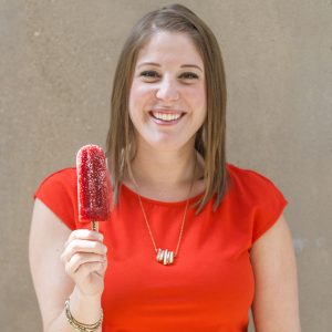Sustainability grad Carolyn wearing bright red top and holding dark red popsicle