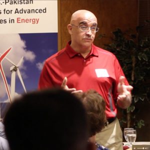 Professor stands in front of a banner displaying a wind turbine