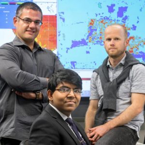 Georgescu and another researcher pose in front of climate models with 16-year-old computer whiz Gupta 