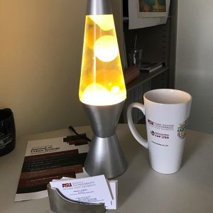 Yellow lava lamp on a table along with a mug and business cards